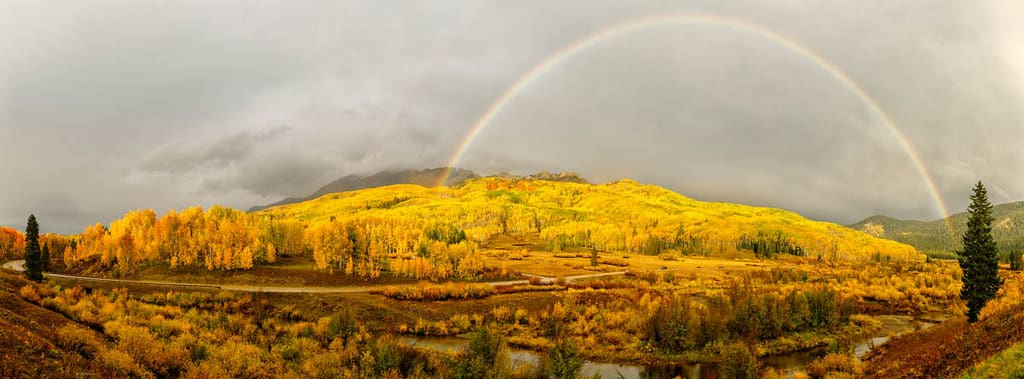 Rainbow over golden aspen mountains